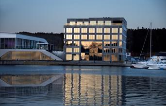 Fasade Mandal Hotel, som speiler seg i Mandalselva ved siden av Buen Kulturhus