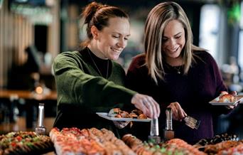 Smilende gjester som forskyner seg av sushi