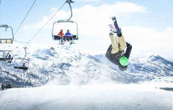 Gutt med ski tar salto i terrengparken, bilde