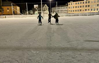Tre jenter som går på skøyter på isbanen