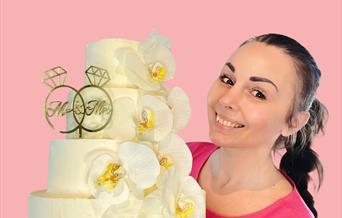 Kvinne som holder en hvit bryllups kake  med blomster detaljer