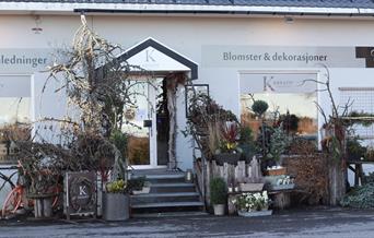 Bilde på utsiden av butikken med masse blomsterdekorasjoner rundt inngangspartiet.