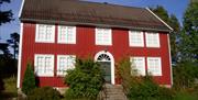 Annen rød bygning med hvite karmer, 9 vinduer og 1 grønn dør