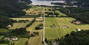 Bilde tatt ovenfor av en vei midt på med åkere og hus på høyre og venstre side