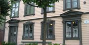 fasade på Kløckers hus - Arendal bymuseum. Beige med mørkegrønne lister rundt vinduene.