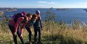 Tre barn på toppen av utsiktpunktet med havet bak seg og åpen himmel
