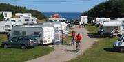 Lindesnes Camping og Hytteutleie, en sti lang mellom campingvognene. To syklister med knallrøde t-skjorter sykler på stien.