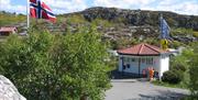 Resepsjonen og kiosken i samme hvite bygningen, norsk flagg på flaggstanga vedsiden av bygningen