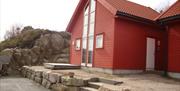 Rød hytte med steinplatting foran