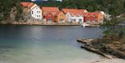 Moderne feriehus i forskjellige farger ved havet, I forgrunnen er en strand.