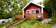 Lindesnes Camping og Hytteutleie - Rød hytte med hvite karmer, har også en terrasse med trapp inn til hytta.