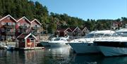 3 store båter står rekke på rad ved brygga, tregde feriehus i bakgrunnen