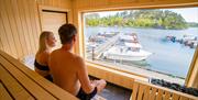 sauna-badstue-tregde-mandal-bading-skjærgård-utsikt. To personer i badstue hos Tregde Sauna. Foto.
