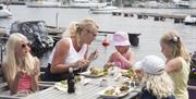 Familie på 5 som sitter ute og spiser god mat