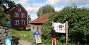 Kort sti fra Merdøgaard museum til infotavle og reklameskilt med is som selges i Kroa rett ved