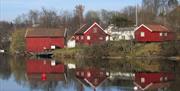 Bomsholmen Fløtingsmuseum med sine tre røde bygninger rett ved Nidelva i Arendal