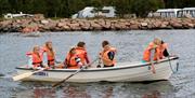 Barn som er ute i robåt på vannet utenfor campingplassen