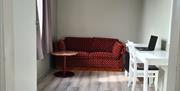 Lyst rom med hvit pult og stol. Rød toseters sofa med fargerike prikker.