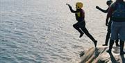 Coasteering gutt har tatt steget fullt ut og er på vei ned i sjøen.