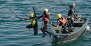 Coasteering deltakere hopper i sjøen fra båten