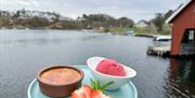 En nydelig blå tallerken  pyntet med oppskåret jordbær og blåbær. En brun skål med creme brulle, og en hvit dyp skål med mørk rosa jordbær sorbe oppå tallerkenen