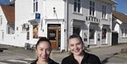 To smilende jenter med brød i armene foran bakeriet