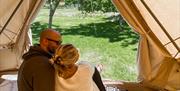 et par som sitter på en seng i et glamping telt