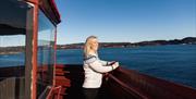 Dame som står oppe i fyret på Hatholmen og ser ut over havet