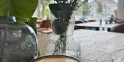 En kopp cappuccino og blomster på bordet på Herlighed