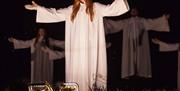 En gruppe engler i hvite kapper står med åpne armer på scenen under nattehimmelen i «Veien til Betlehem» i Lyngdal.
