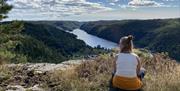 Nomeheia i Øyslebø. En i hvit topp og gul bukse sittende og ser framover. skog til høyre og venstre med elv midt i.