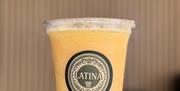Gul smoothie i plastbeger med Latina-logo.
