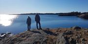 To mennesker bakfra, med utsikt utover havet fra Kalvehageneset
