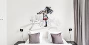 hotellrom med streetart på vegg over seng forestillende liten jente med blåseinstrument.