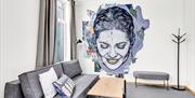 Hotellvegg med streetart på veggen som forestiller et kvinnehode som smiler og kikker ned