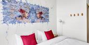 hotellvegg med streetart forestillende to kvinnehoder mot lyseblå bakgrunn.