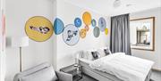 hotellvegg med streetart som forestiller sirkler i forskjellig størrelse i gult, blått og grått med fugler i.