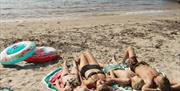 Familie på fire som soler seg på stranden