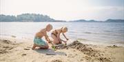To barn som lager sandslott på stranden