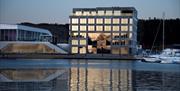 Fasade Mandal Hotel, som speiler seg i Mandalselva ved siden av Buen Kulturhus