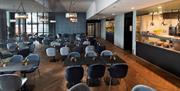 Frokostsal Mandal Hotel.  Brun fiskebeingulv med mange svarte bord og stoler. Varmmat buffe på venstre side.