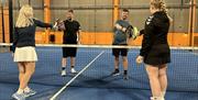 To damer og to menn som hilser på hverandre med padel rackertene sine før kamp