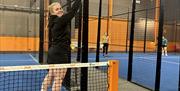 En dame som legger til et poeng med padel rackerten  sin