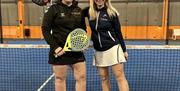 To damer som poserer foran en padel bane