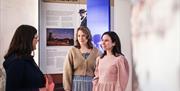 Et par som får omvisning i en av utstillingene i Andorsengården av en museumsformidler
