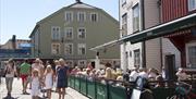 fullt med mennesker på uteserveringen til Strand Kafe i havna Pollen i Arendal