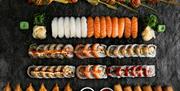 Bilde tatt fra oven av et bord med masse forskjellig sushi, vårruller, dumplings og kylling sticks