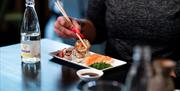 Talerken med sushi og en flaske med mineralvann ved siden av