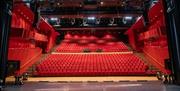 teater- og konsertsal med 20 rekker røde plysjstoler skrånende ned mot scenen.