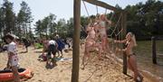 Mange mennesker på en strand, to jenter leker i en nettingvegg